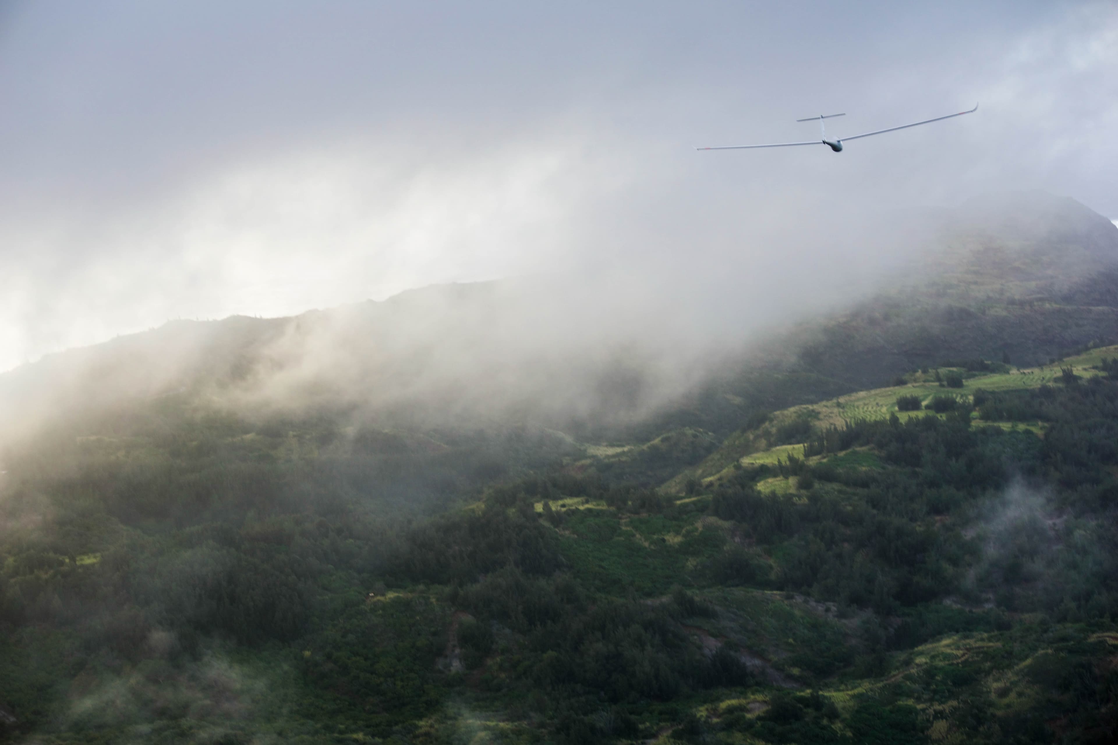 Glider above misty North Shore ridgelines.